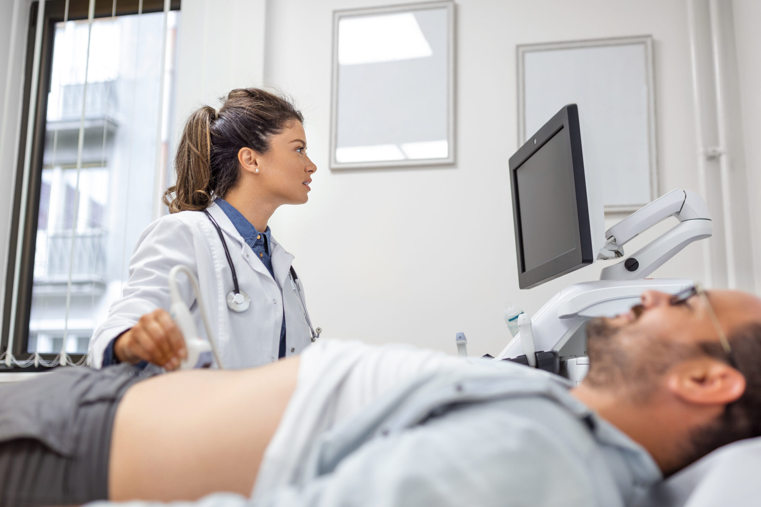 careful-female-doctor-white-coat-sitting-front-ultrasound-apparatus-conducting-abdominal-diagnostics-with-transducer-scaled